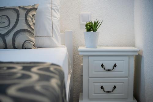 a bed and a nightstand with a potted plant on it at Apartmani Kaštelina in Vir