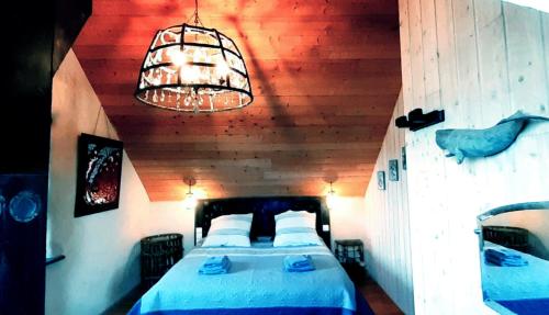 a bedroom with a bed and a chandelier at L'écurie Kerdoel in Cléder