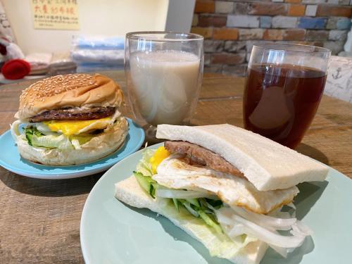 台東市的住宿－陽光鹿特丹台東民宿，两个盘子,夹三明治和一杯牛奶