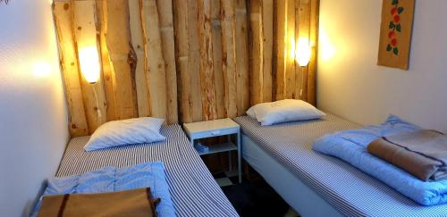 two twin beds in a room with a wooden wall at Stuga ROS Naturcamping Lagom in Gräsmark