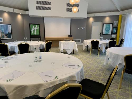 a room with tables and chairs with white table cloths at Holiday Inn Dover by IHG in Dover