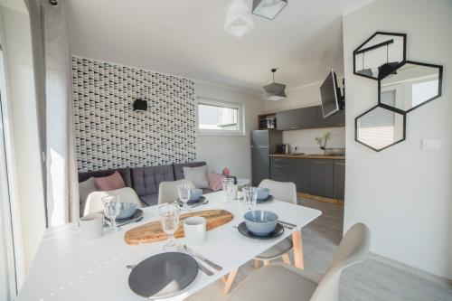 a dining room and kitchen with a white table and chairs at Zagroda Wrzosowa in Dębki