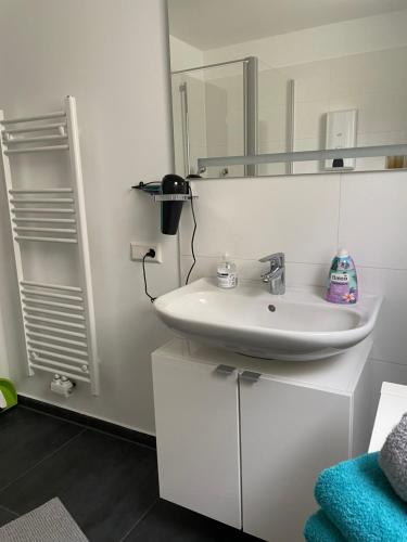 a white bathroom with a sink and a mirror at Ferienwohnung mit Waldblick in Leimen