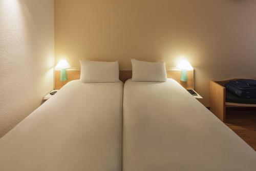 a large bed with two pillows in a room at ibis Nürnberg Hauptbahnhof in Nürnberg
