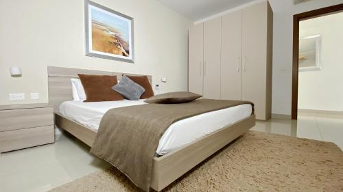 a white bedroom with a large bed and a rug at Quisisana Apartments - Cast Renting in Sliema