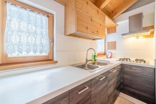 una cucina con lavandino e finestra di Appartamenti Al Molin ad Alleghe