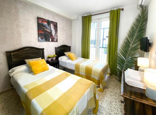 a hotel room with two beds and a window at Hostal Azahara in Nerja