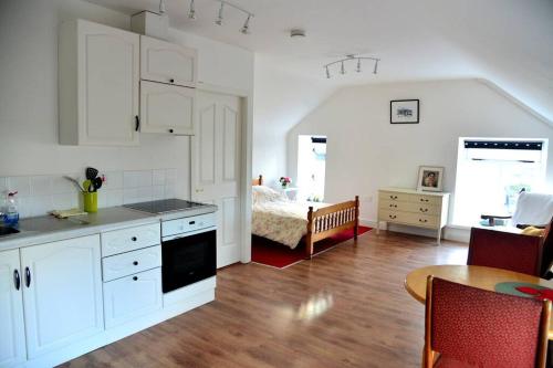 a kitchen with white cabinets and a bedroom with a bed at Camp Street Studio Room 4 in Oughterard