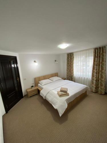 a bedroom with a large white bed and a window at Casa Violetei in Bran