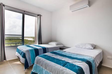 a bedroom with two beds and a large window at DEPARTAMENTO DE LUJO 3 RECAMARAS EN EXCLENTE UBICACION in Cancún