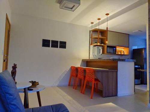a kitchen with a bar with orange chairs in it at Guarajuba Paraíso dos Coqueiros in Guarajuba