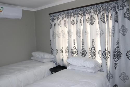 a bedroom with two beds and a curtain at Tlelakufuma Guest House in Johannesburg