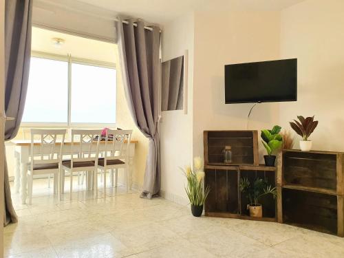 a living room with a television and a dining room at Superbe appartement face à la mer avec parking privatif in Canet-en-Roussillon