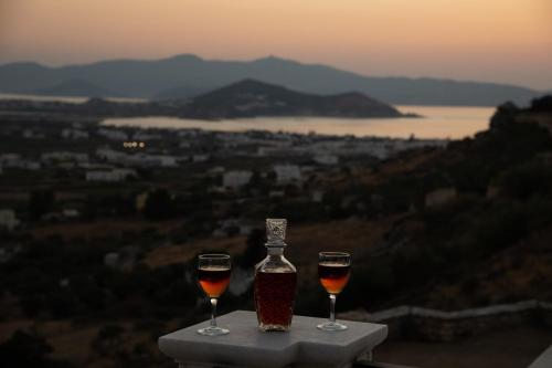 due bicchieri di vino seduti su un tavolo con una bottiglia di Alta Vista Naxos a Naxos Chora