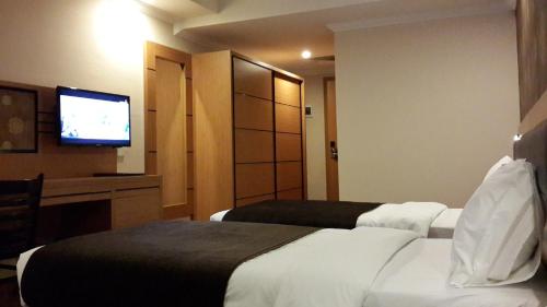 a hotel room with a bed and a flat screen tv at Merci Hotel Erbil in Erbil