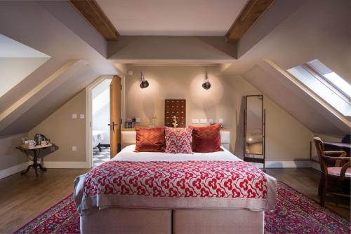 a bedroom with a large bed with a red comforter at The Howard Arms in Ilmington
