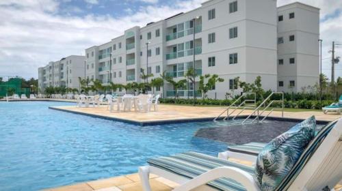 a swimming pool with chairs and a building at Palm Village - Porto de Galinhas/Cupe/Muro Alto in Porto De Galinhas