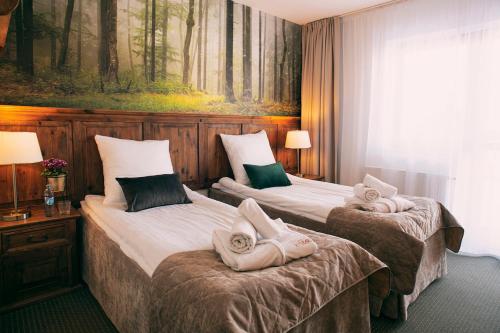 two beds in a hotel room with towels on them at Hotel Kotarz Spa&Wellness in Brenna