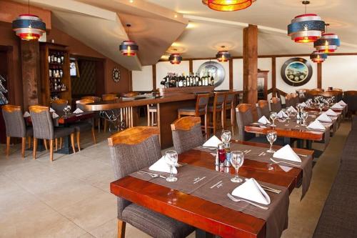 Un restaurante con mesas y sillas de madera y un bar. en Apartman NERA - u Kraljevim čardacima Kopaonik, en Kopaonik