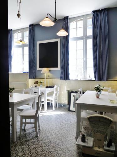 ein Esszimmer mit weißen Tischen und blauen Vorhängen in der Unterkunft Huis Vandermersch in Ypern