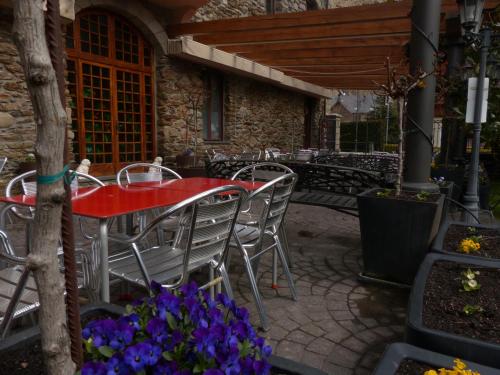 a red table and chairs on a patio with flowers at Hostal Vall D'Aneu by Arcas & Sambola in Esterri d'Àneu