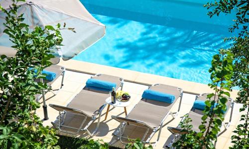 Grand View Villa Private Heated Pool في Georgioupoli: مجموعة كراسي ومظلة بجانب مسبح