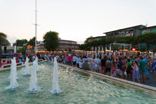 ビビオーネにあるApartments in Bibione 24392の噴水の周りに立つ大勢の人々