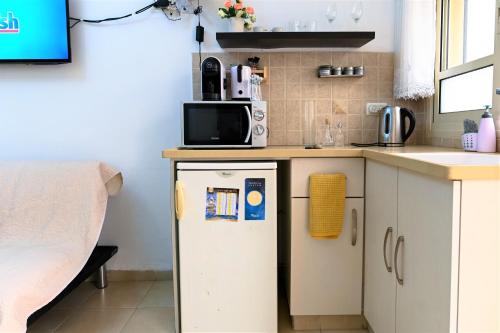 a small kitchen with a refrigerator and a microwave at Domos Tiberias דומוס טבריה in Tiberias
