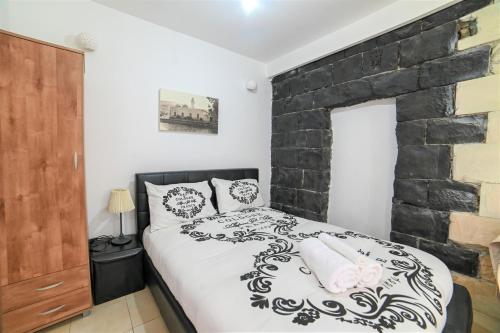 a bedroom with a black and white bed and a brick wall at Domos Tiberias דומוס טבריה in Tiberias