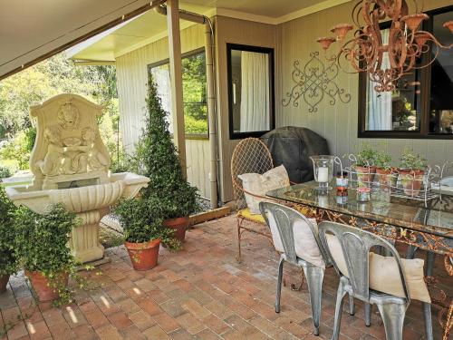 eine Terrasse mit einem Brunnen, einem Tisch und Stühlen in der Unterkunft La Belle Vie Bed & Breakfast in Napier