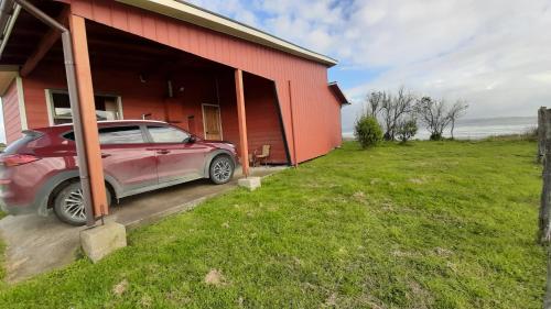 a car parked outside of a red building at CABAÑAS MAR BRAVA in Ancud