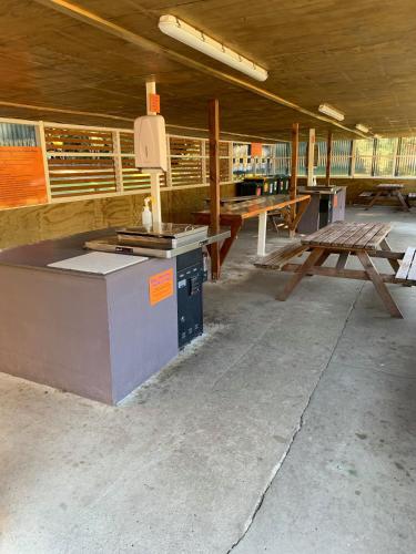 an empty building with a stove and picnic tables at Sapphire Springs Holiday Park and Thermal Pools in Katikati