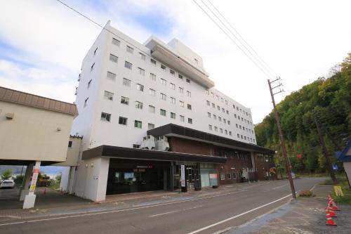 a large white building on the side of a street at Toya-onsen Hotel Hanabi in Lake Toya
