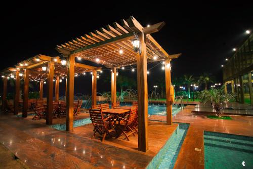 a pavilion with tables and chairs and a pool at night at Seven Seas Hotel in New Delhi