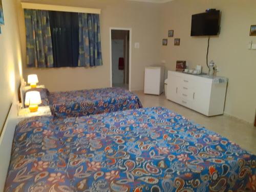 a bedroom with a bed and a dresser and a television at Black Gold Private Room in Msida
