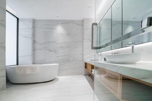 a white bathroom with two sinks and a tub at Shangrao International Hotel in Shangrao