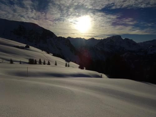a snow covered mountain with the sun in the sky at SunAlpin - Ferienwohnungen in Schoppernau