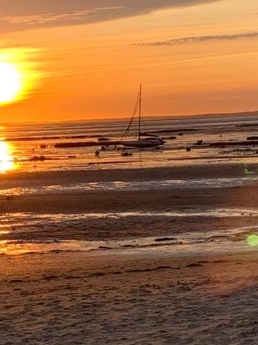 a boat sitting on the beach at sunset at Hôtel la petite auberge in Arès
