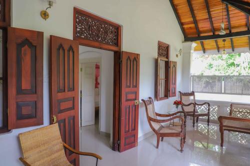 a room with wooden doors and a table and chairs at ilamparuma Hotel in Weligama