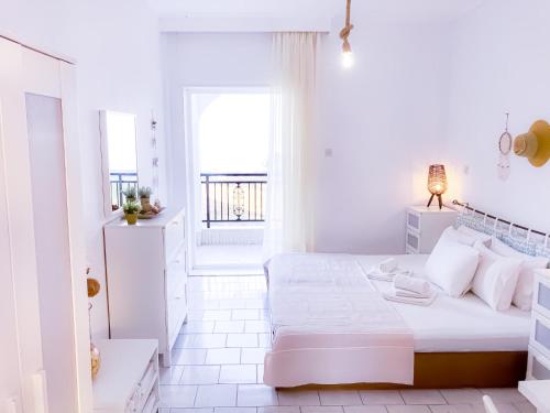 a white bedroom with a bed and a window at VILLA MARAVGIA APARTMENT B in Akti Salonikiou