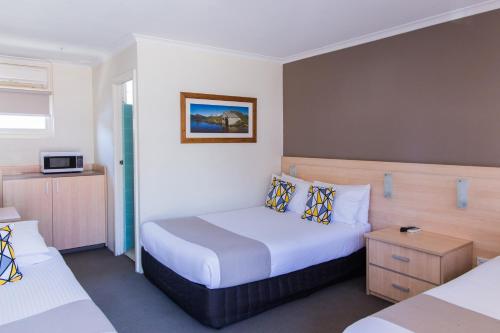 a hotel room with two beds and a tv at Kite Street Units - Contactless Check in in Orange