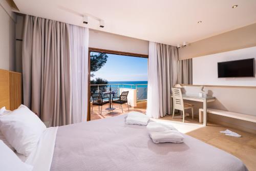 Olympion Sunset Halkidiki في فوركا: غرفة نوم مع سرير ومكتب وإطلالة على المحيط
