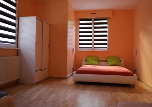 een slaapkamer met oranje muren en een bed met groene kussens bij Commealamaison in Saint-Louis