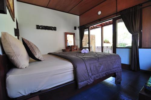 een slaapkamer met een bed met paarse lakens en een raam bij Ana Warung & Bungalows in Gili Meno