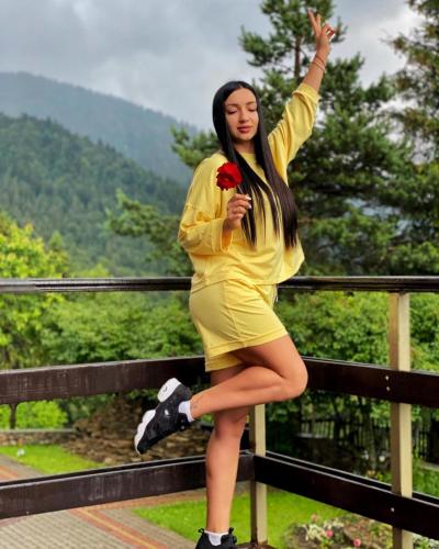 a woman in a yellow dress standing on a fence at Kamyanka in Mizhhirʼʼya