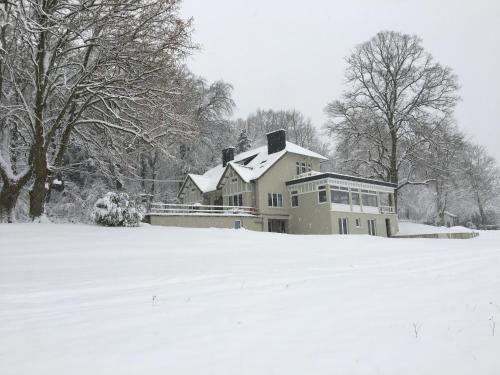 a house covered in snow in a field at La Villa du Pré Du Cerf in Spa