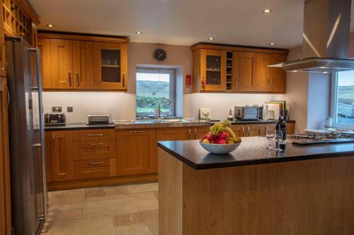 a kitchen with wooden cabinets and a bowl of fruit on a counter at Kentraw Farmhouse Luxury Self Catering in Bruichladdich