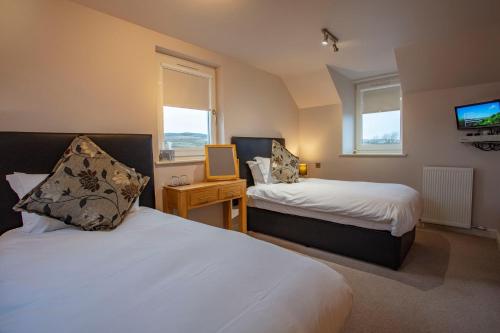 a hotel room with two beds and a television at Kentraw Farmhouse Luxury Self Catering in Bruichladdich