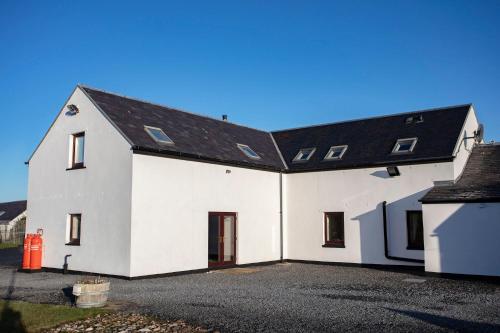 a white house with a black roof at Kentraw Farmhouse Luxury Self Catering in Bruichladdich