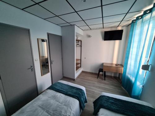 a bedroom with two beds and a television in it at Berry Hôtel La Châtre in La Châtre